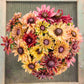 Colorful flower arrangement with saraha black eyed susans against a textured wall.