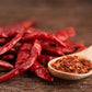 Several slender, Cayenne Long Red Thin peppers are shown with pepper flakes peppers.