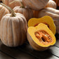 Autumn Frost Squash on a wooden table showing orangish skin and one cut open revealing the orange flesh.